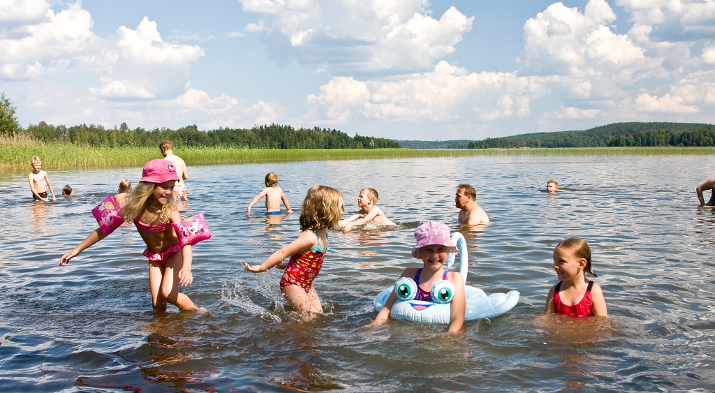 Lapsia leikkimässä uimarannan matalassa vedessä.
