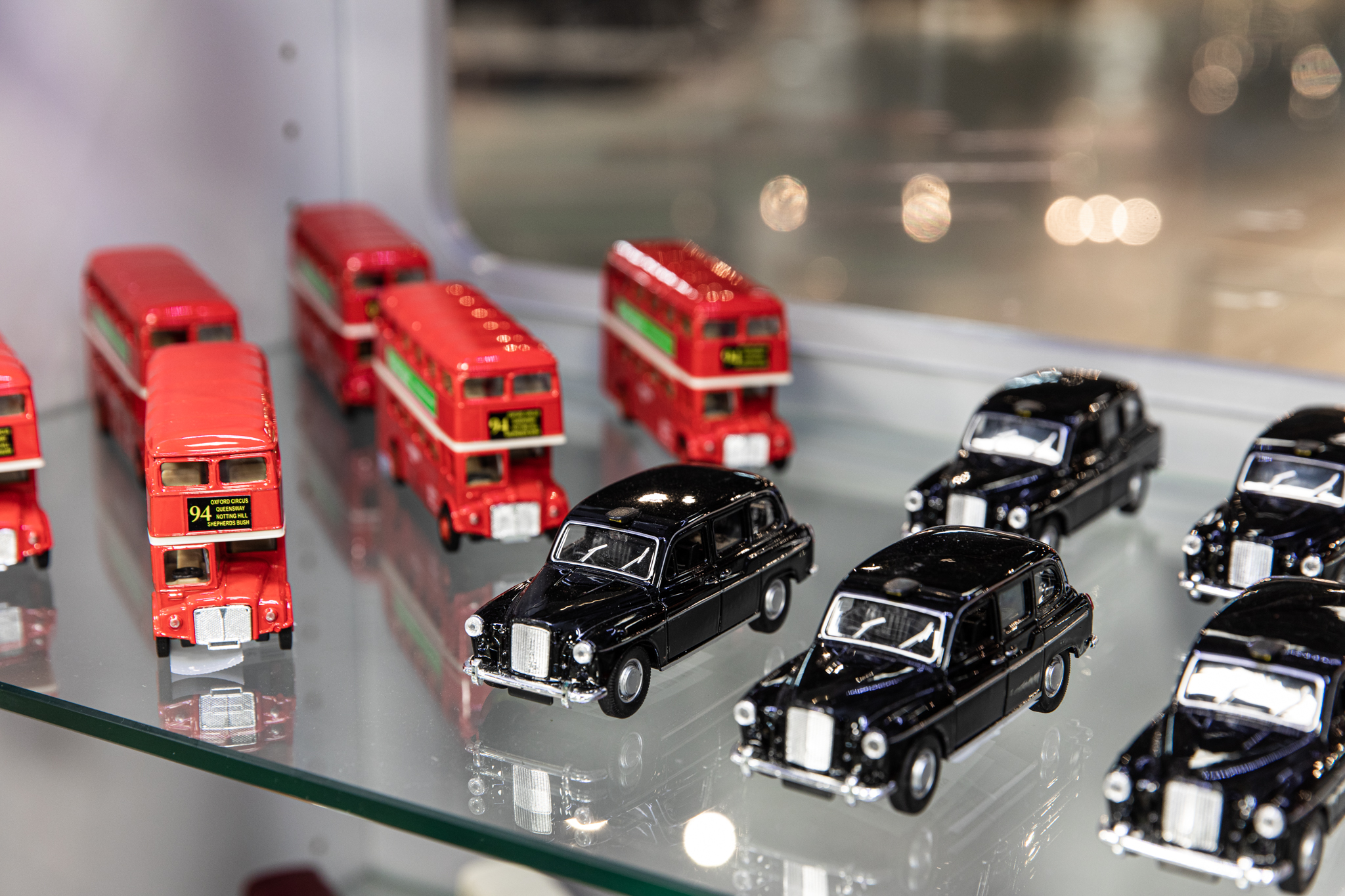 Museokaupan vitriinissä myynnissä punaisia kaksikerrosbusseja ja mustia takseja.