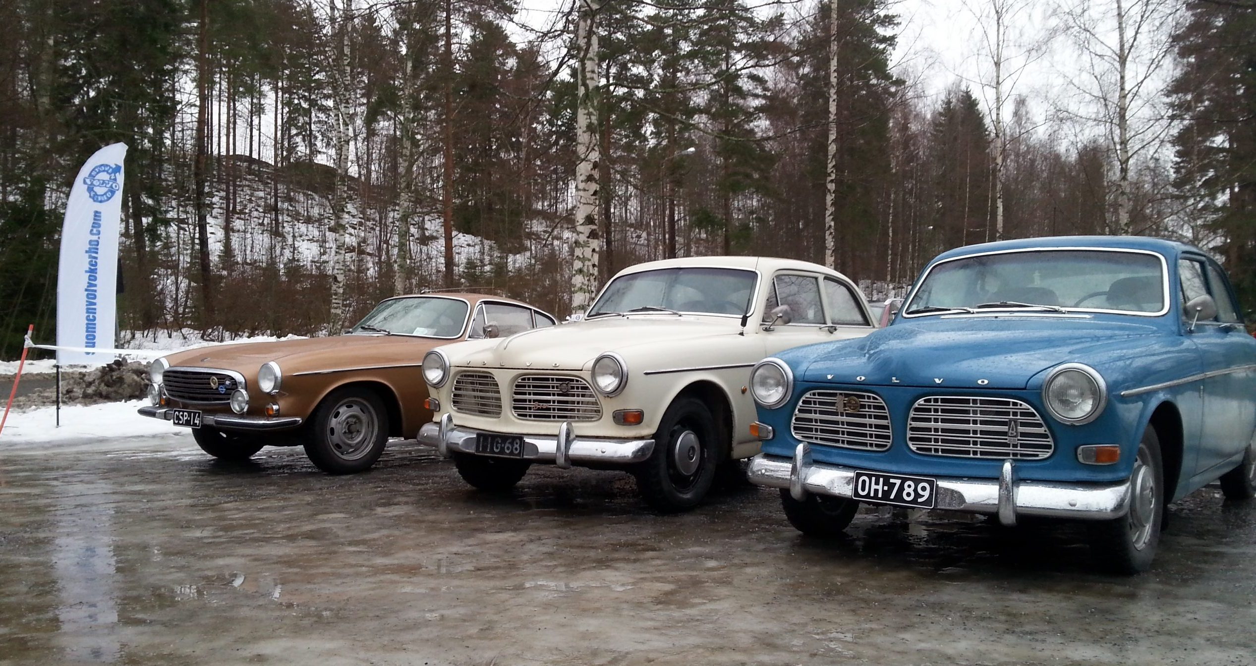 Kolme vanhaa, komeassa kunnossa olevaa Volvoa rivissä talvisella parkkialueella.