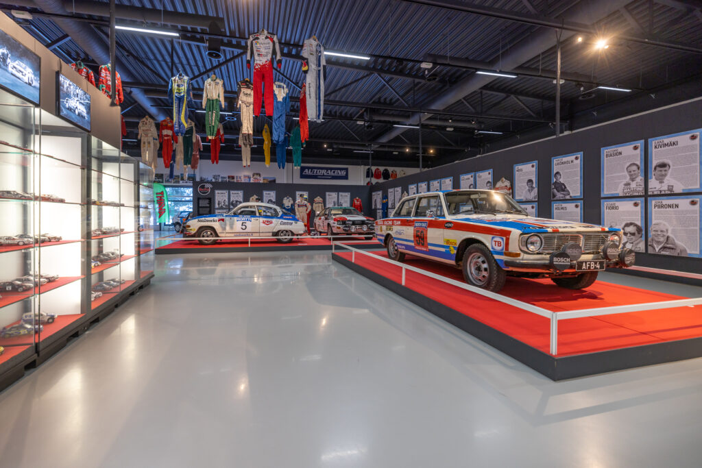 Rallimuseon näyttelytilassa on vanhoja ralliautoja punaisten mattojen päällä, seinillä pienoismalleja valaistuissa vitriineissä ja Rally Hall of Fameen aateloitujen tietotauluja. Katosta roikkuu ajopukuja.