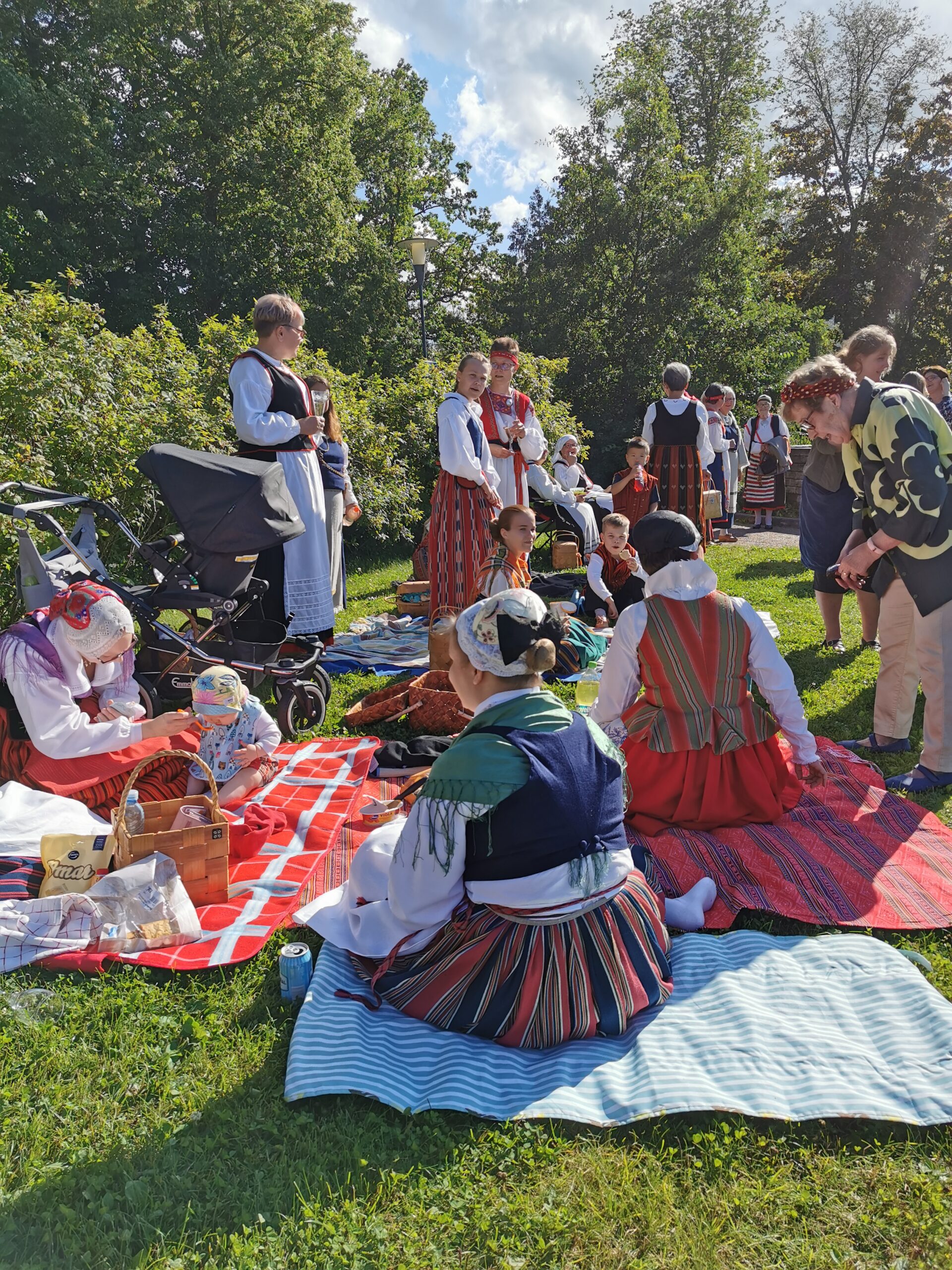 Kansallispuvussa olevat naiset pyyhkeiden päällä nurmikolla