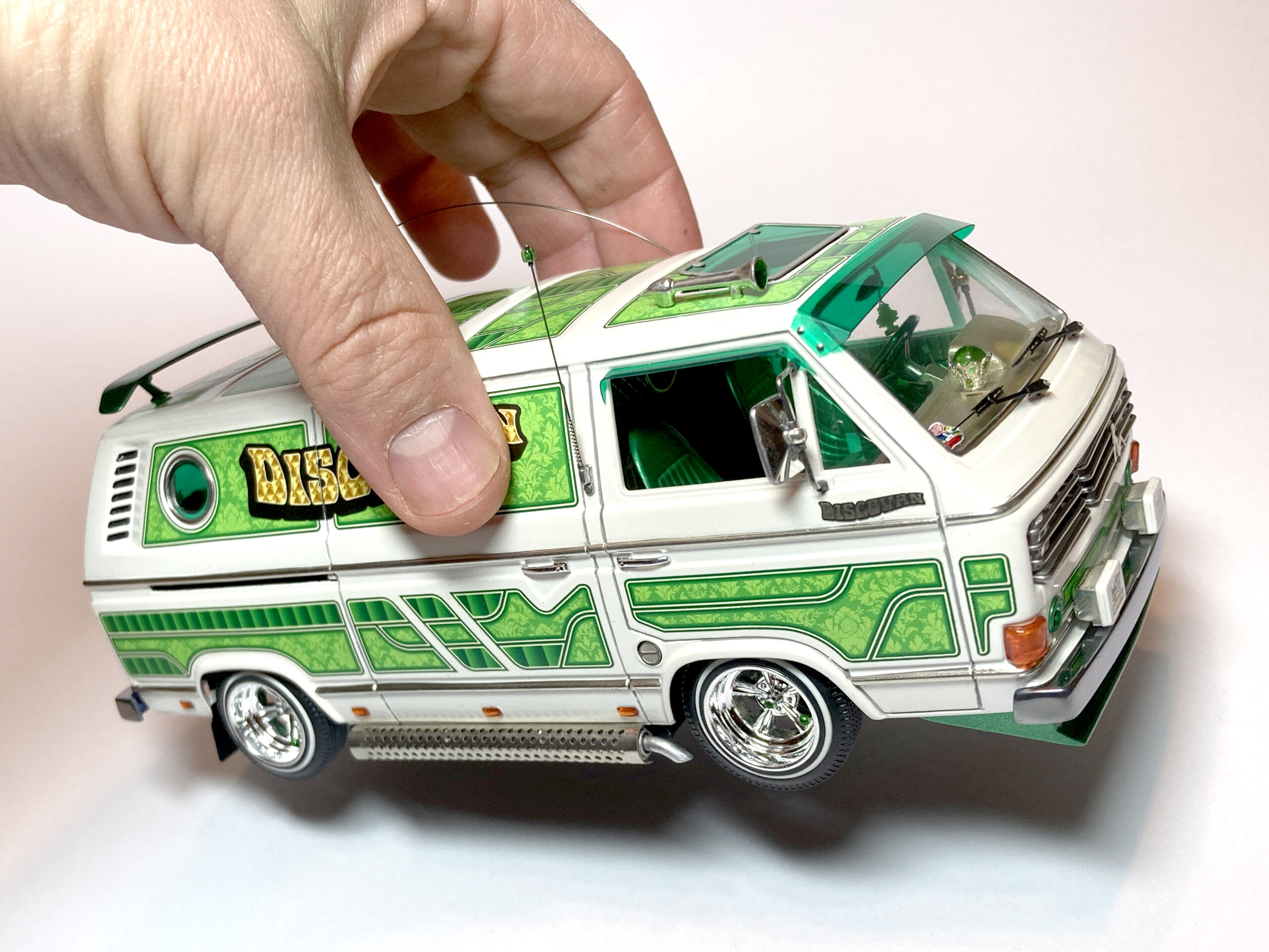 Pienoismalli vihreästä pakettiautosta, josta pidetään kädellä kiinni.