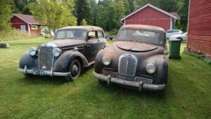 Nurmikolla kuvattu edestäpäin kaksi hyvin pölyistä vanhaa autoa Mercedes-Benz 170 S ja Austin A70 Hereford.